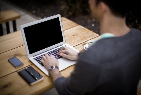 Mann schreibt auf einem Laptop